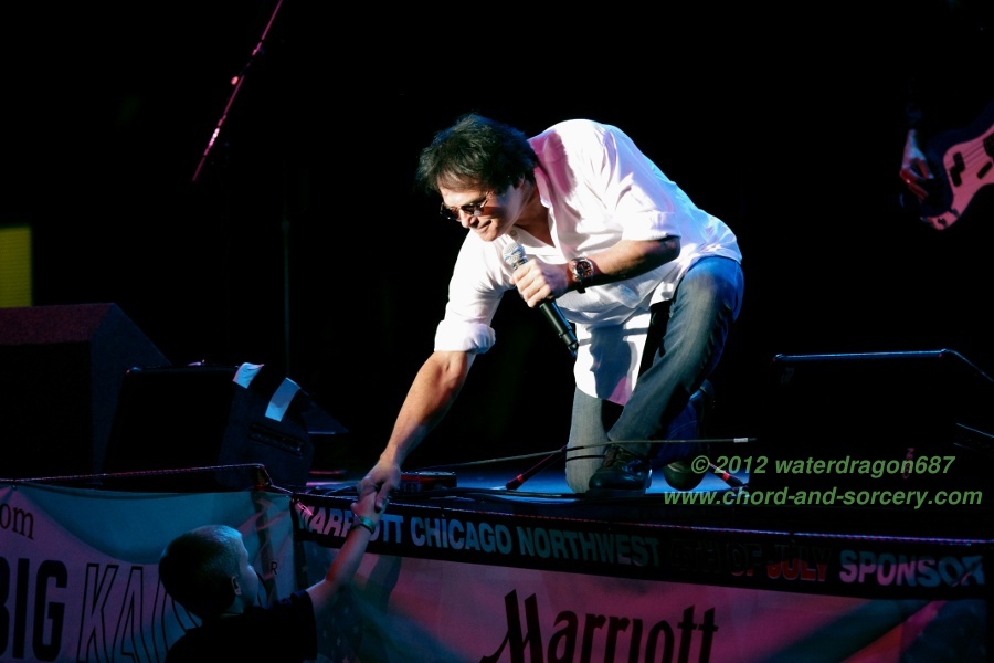 Jimi Jamison (and an unidentified young fan) live in Hoffman Estates, Illinois, 7 July 2012. Photo copyright waterdragon687, all rights reserved; not to be reproduced without permission.
